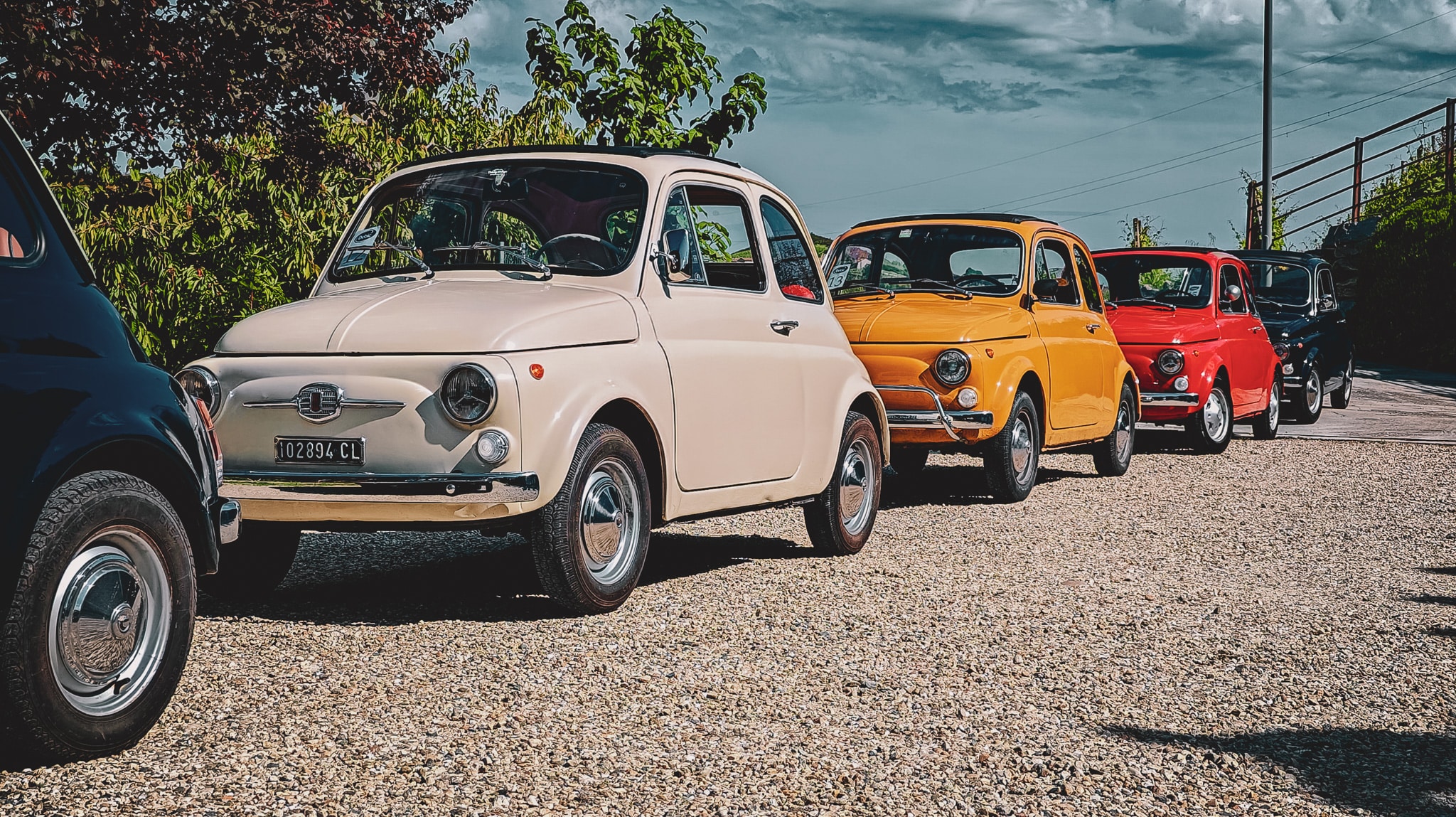 Enkele oude Fiat 500's in verschillende kleuren achter elkaar