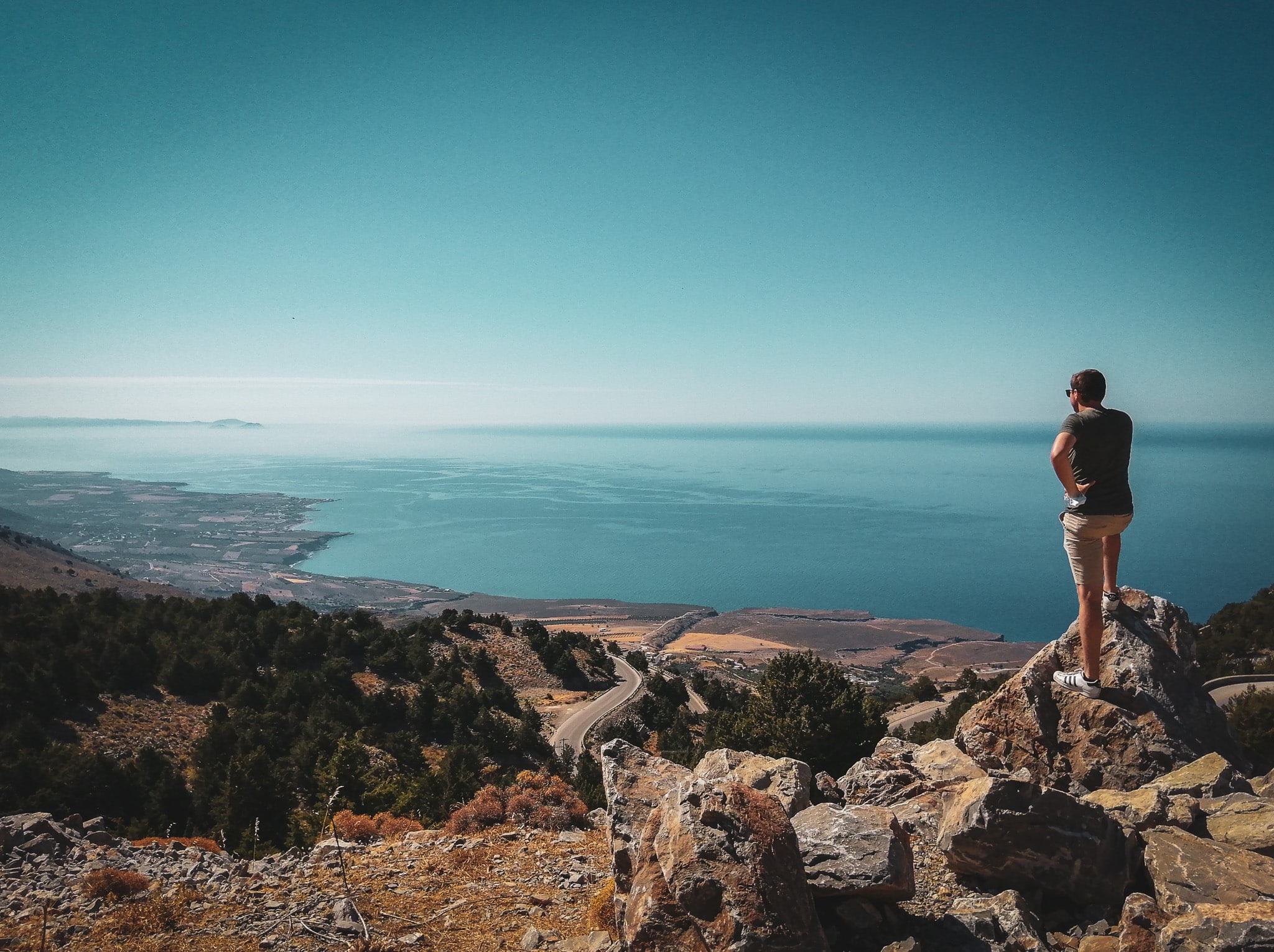 Man staat op een rots op Kreta en kijkt uit over zee